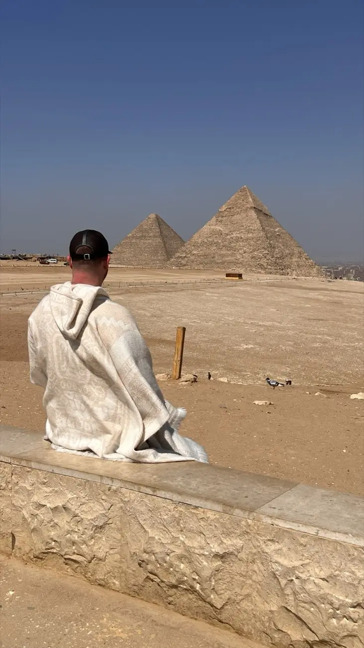 Jonas sitzt auf einem Stein und blickt auf die Cheops-Pyramide